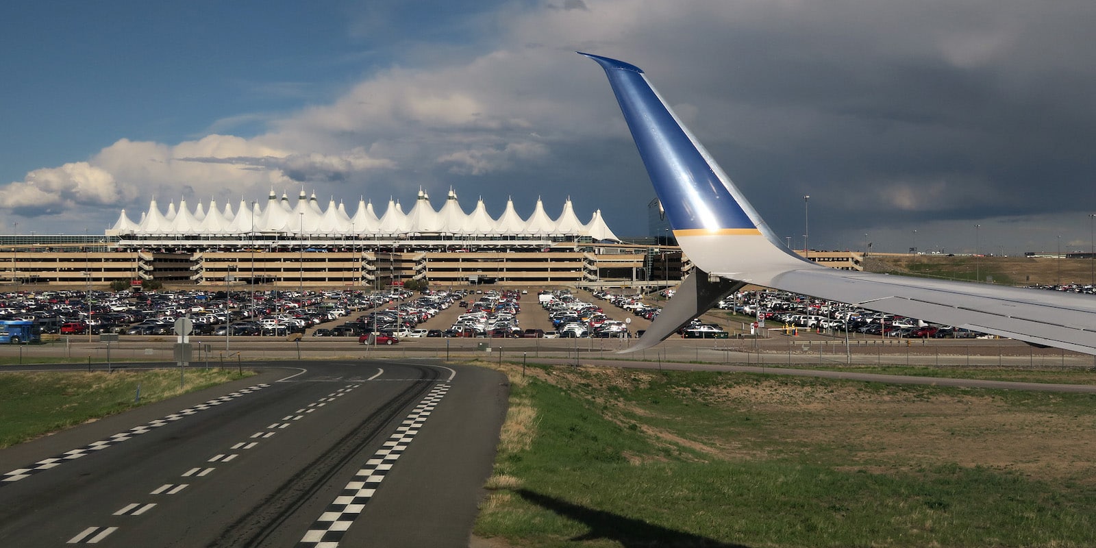 Image of an airplane wing with the Denver International Airport in the background