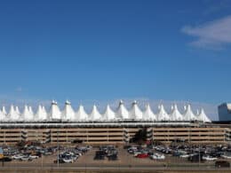 Exterior photo of the outside of Denver International Airport showing outside parking, covered parking garage, Jeppesen Terminal and Westin Airport Hotel