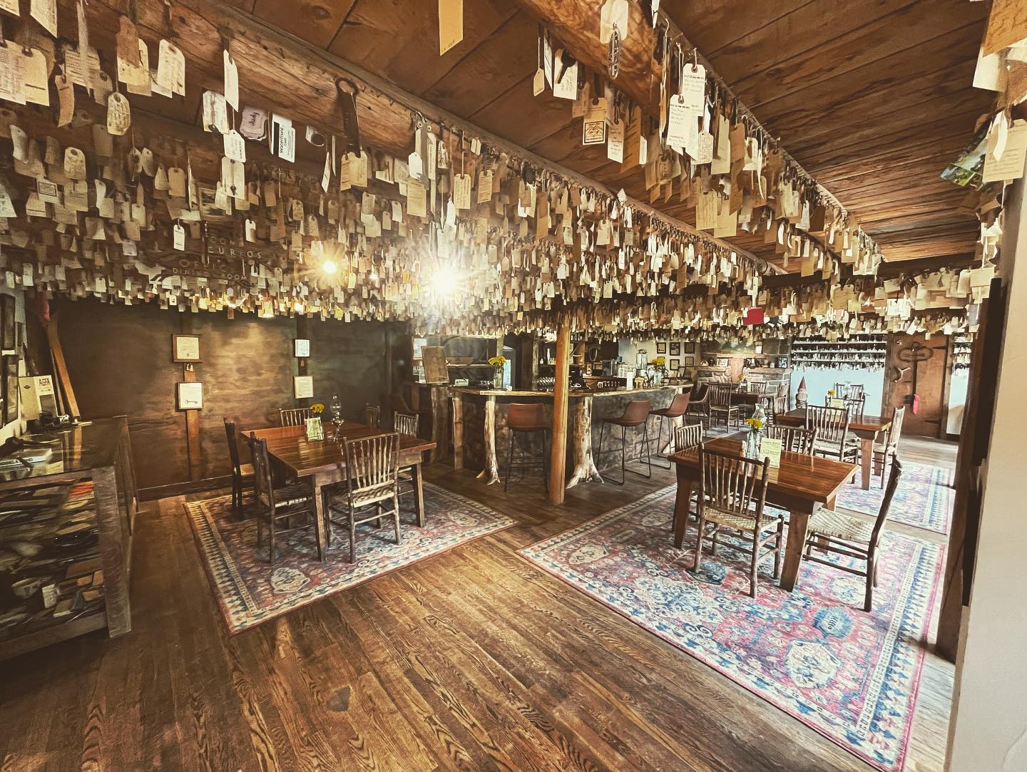 Large dining room at Seven Keys Lodge with dark wood accents, dining tables, and old hotel paper key tags hanging from the ceiling