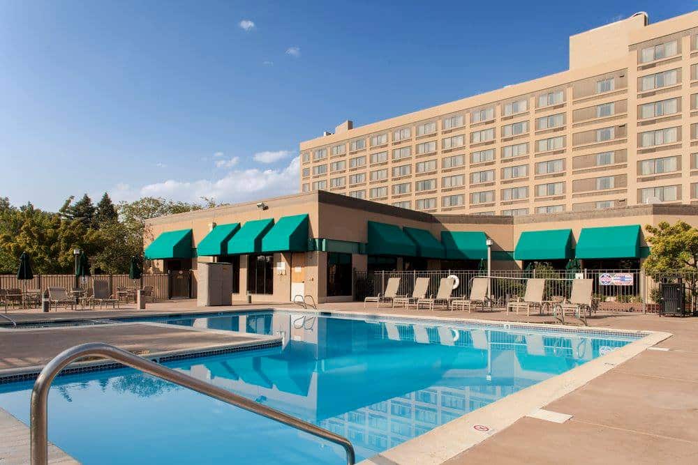 Back of the property at Doubletree Grand Junction with a large outdoor pool and sun chairs