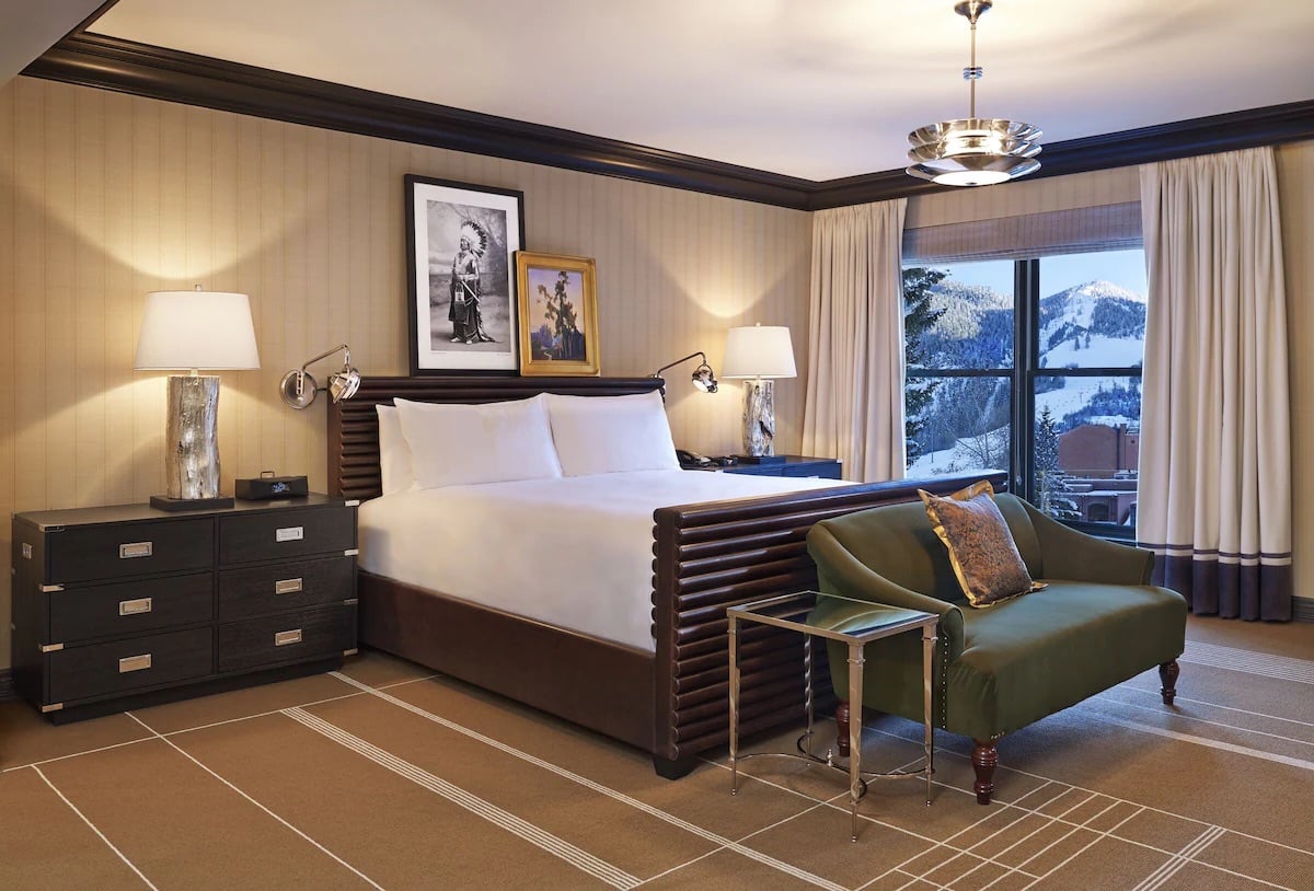 Junior Suite with queen bed with a window looking out to Aspen Mountain in the winter at Hotel Jerome