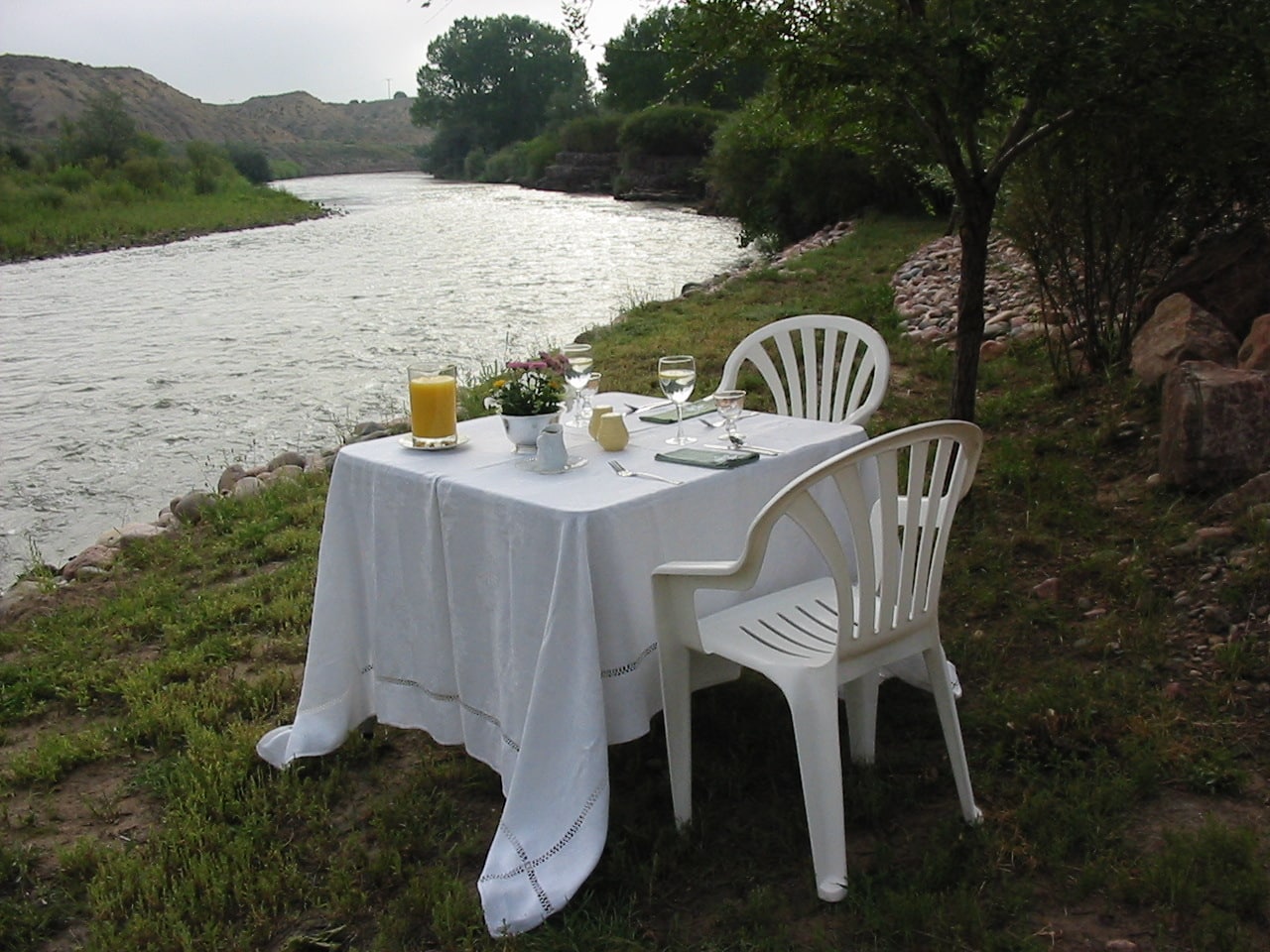 Breakfast table set up by the river at Larking B&B