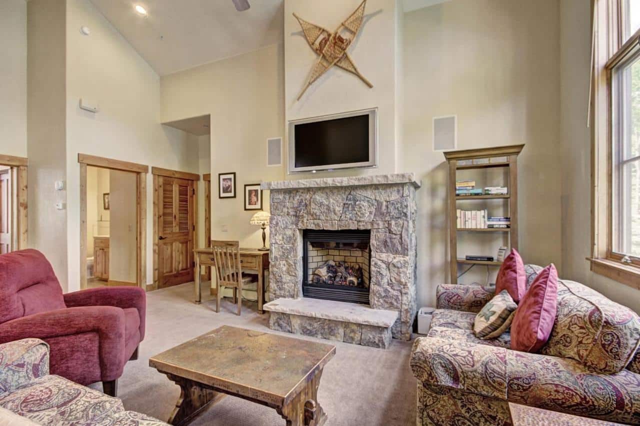 Large living room in a suite at Thunder Mountain Lodge in Breckenridge. Large stone fireplace and 3 plush couches