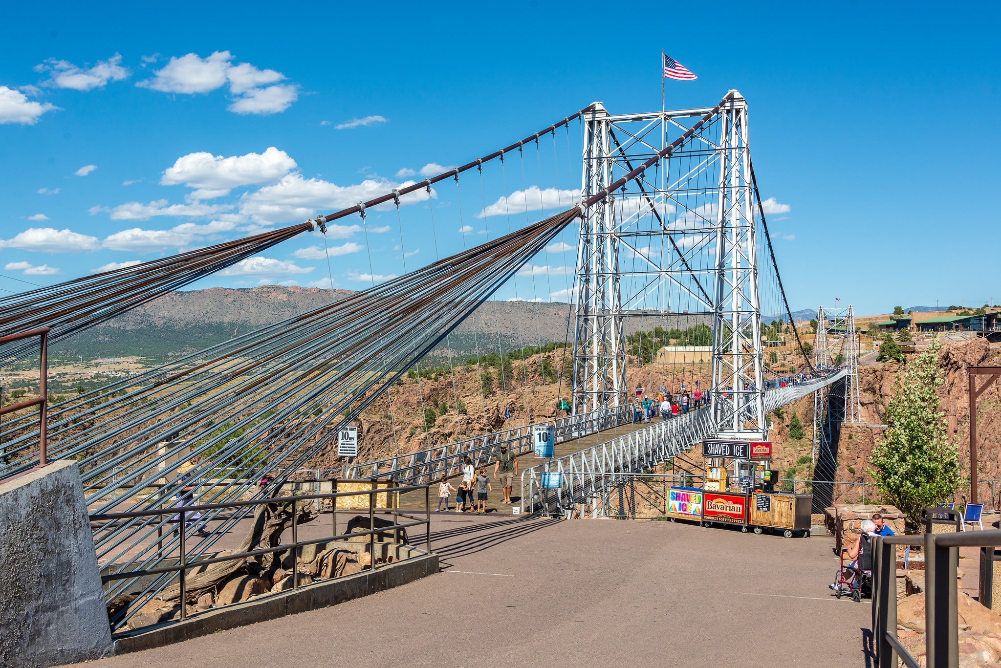 One end of the Royal Gorge Bridge and Park. The bridge is a massive silver suspension bridge with a small American flag waving on one of the support structures.