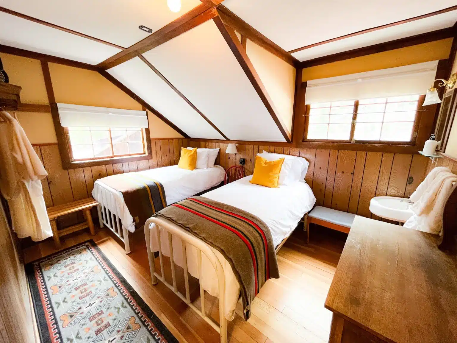 Hotel room with two twin beds, a wooden dresser, and a sink at the Seven Keys Lodge