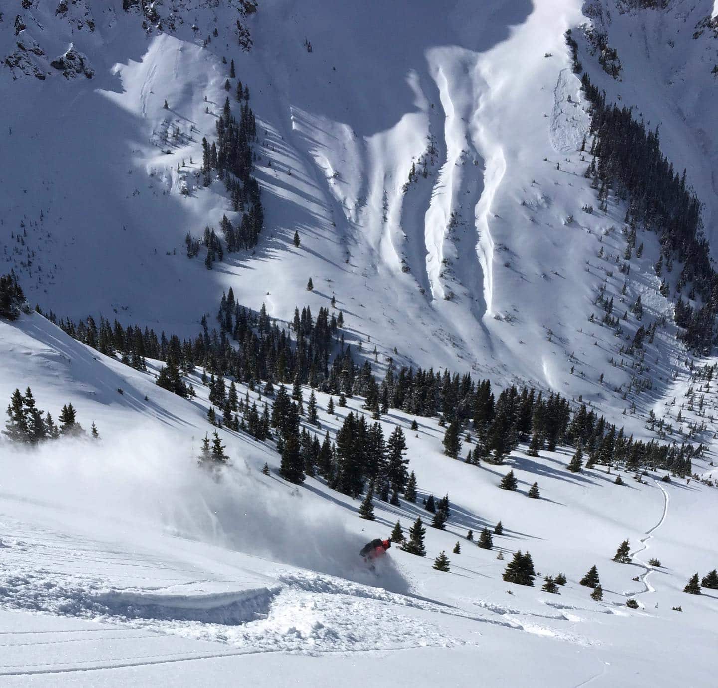 Huge snowy Silverton Mountain with small skier making their way down