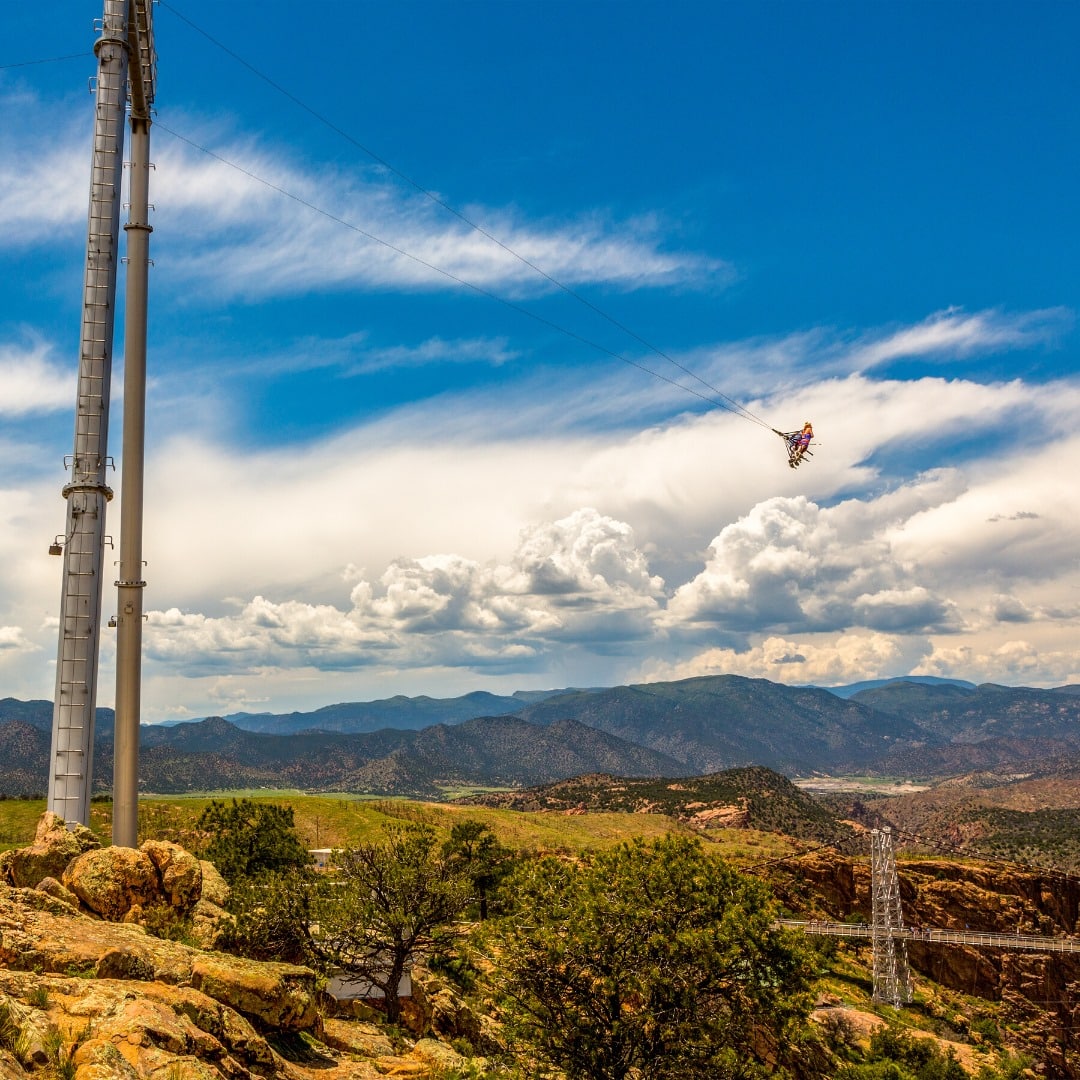 Two people burrito-ed into a safety harness and attached to a large swing over the Royal Gorge Skycoaster