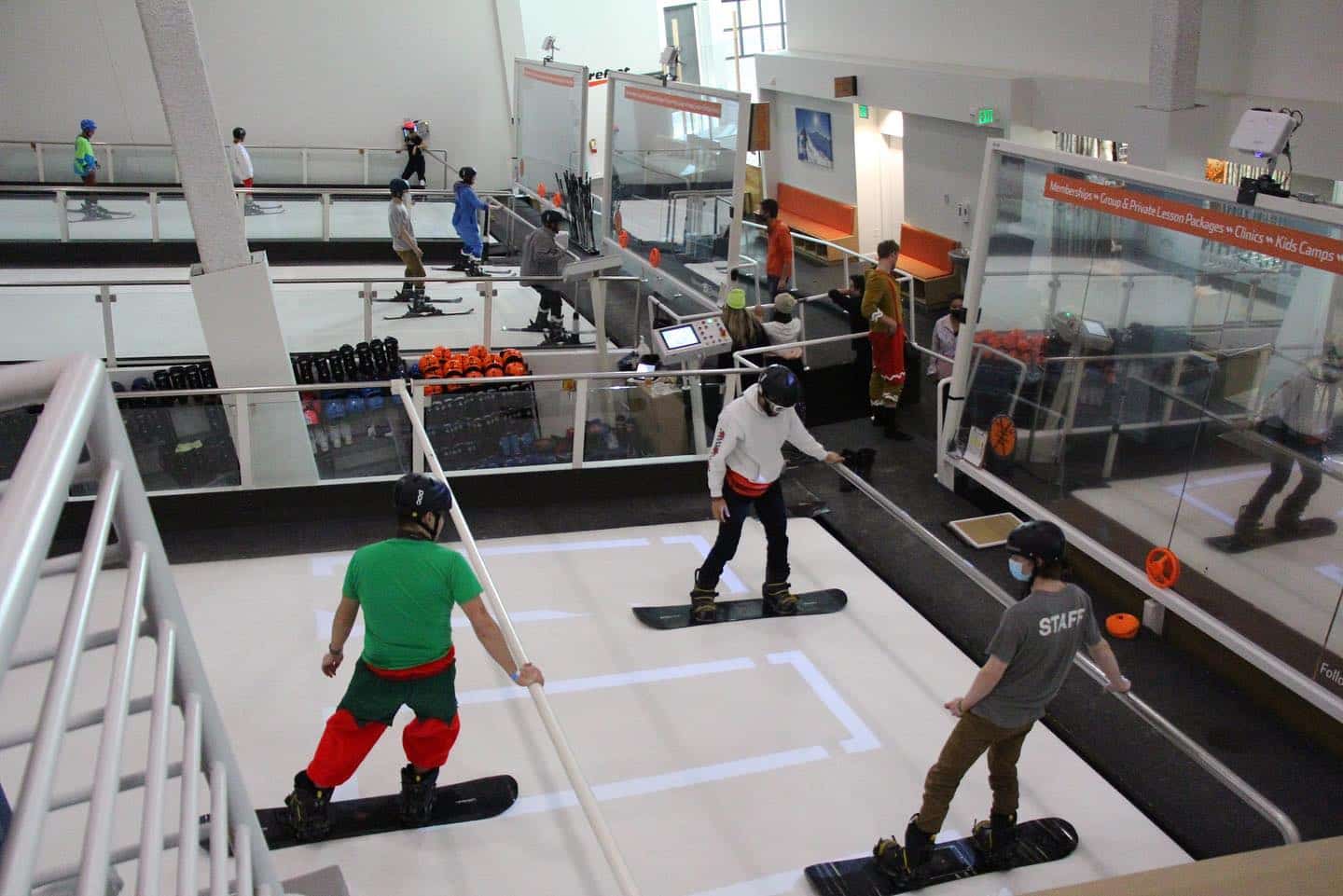 Several people on snowboards on indoor revolving slopes at SNÖBAHN