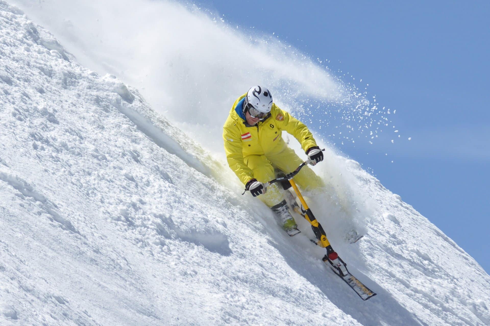 Person in yellow skisuit shredding down a snowy mountain on a snowbike in Breckenridge from Roger's Snowbike Rentals