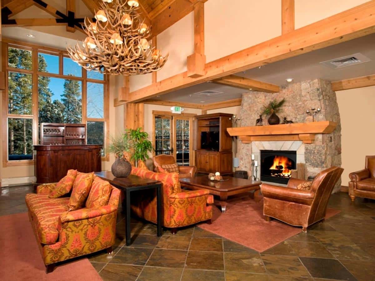 Lobby at Thunder Mountain Lodge with rustic cabin decorations. Stone fireplace, vaulted wooden ceilings, and an antler chandelier. 