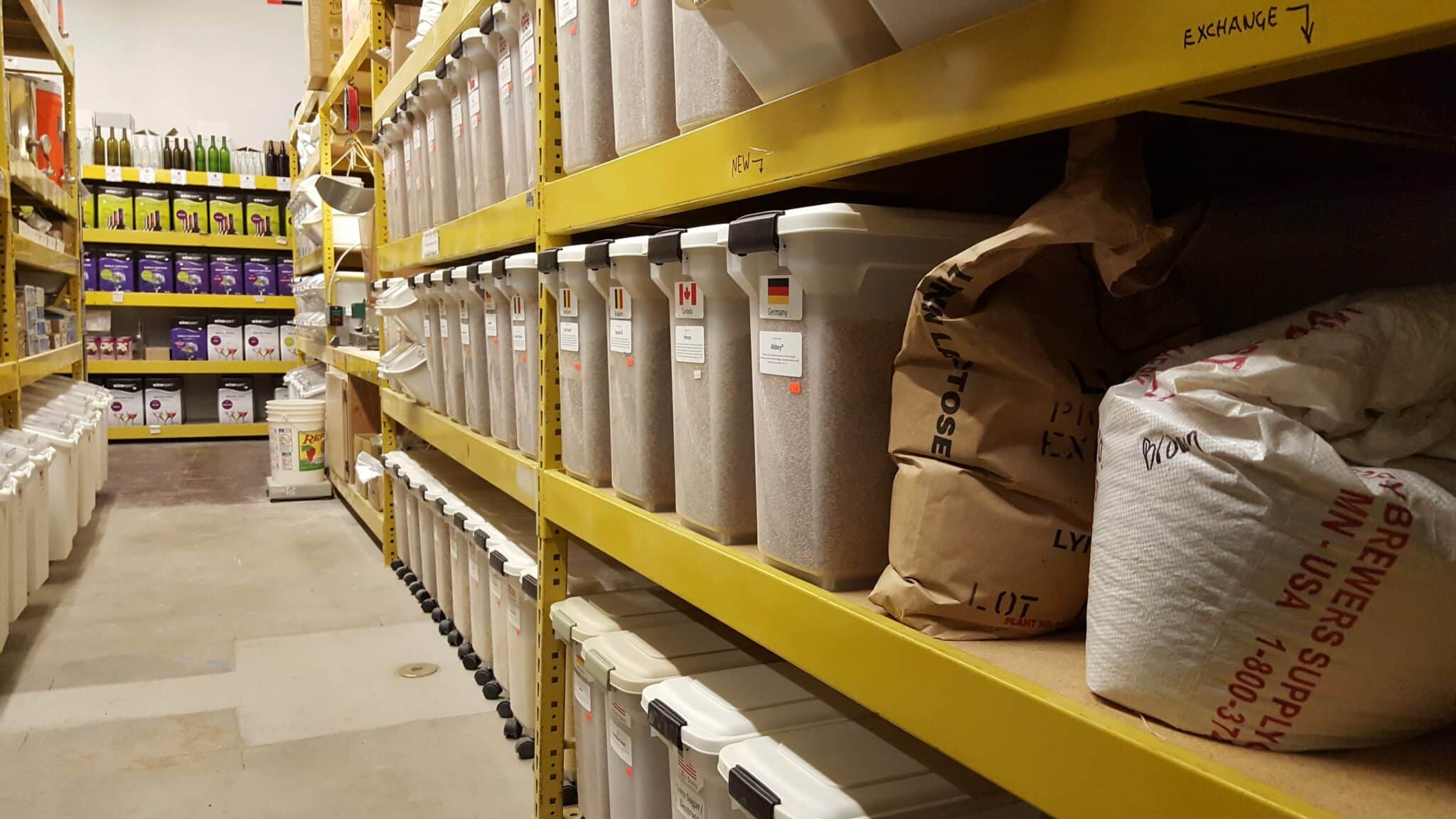 Yellow shelving with plastic containers holding homebrew supplies at Tom's Brew Shop