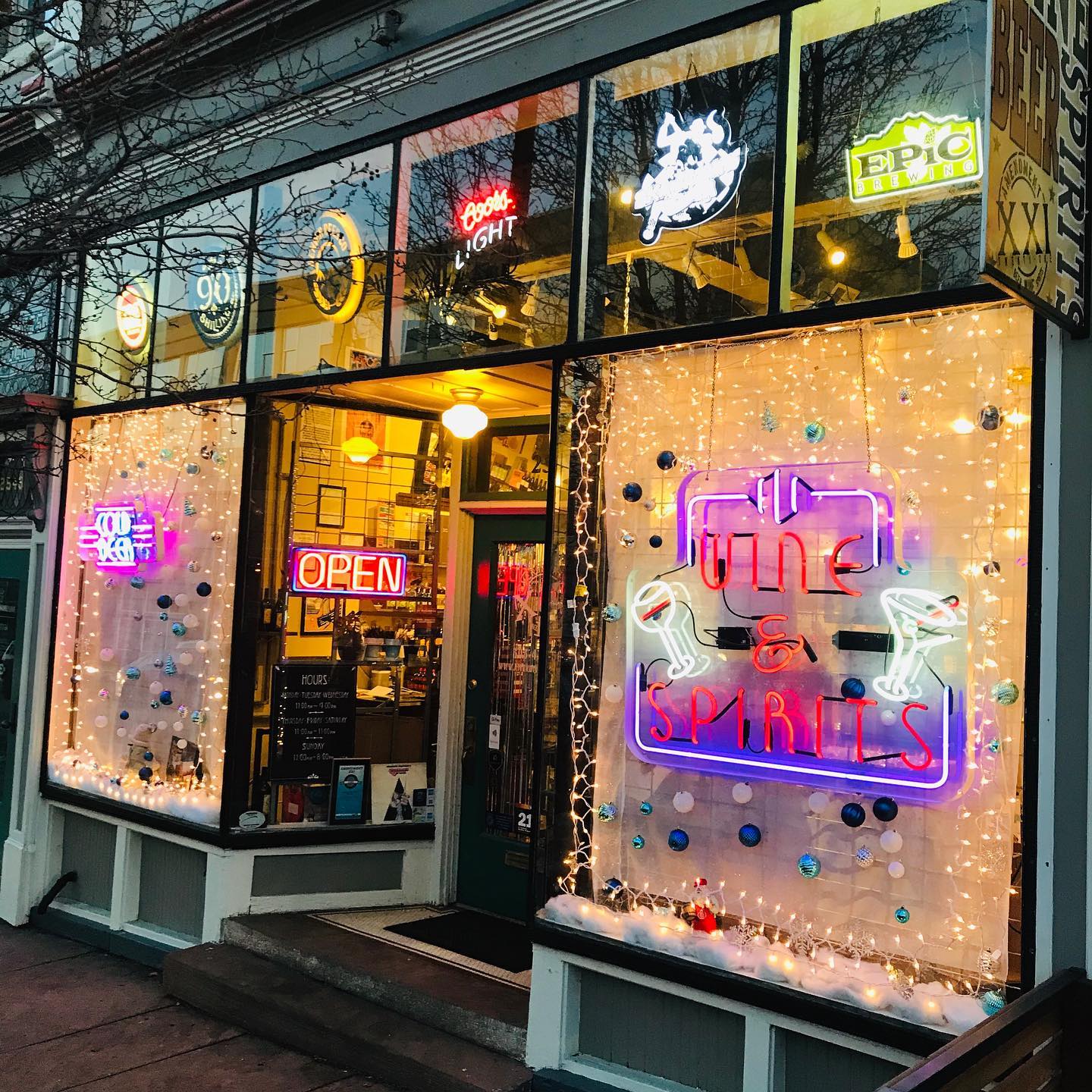 Storefront of Amendment XXI Wine & Spirits with all glass windows and neon signs in Denver