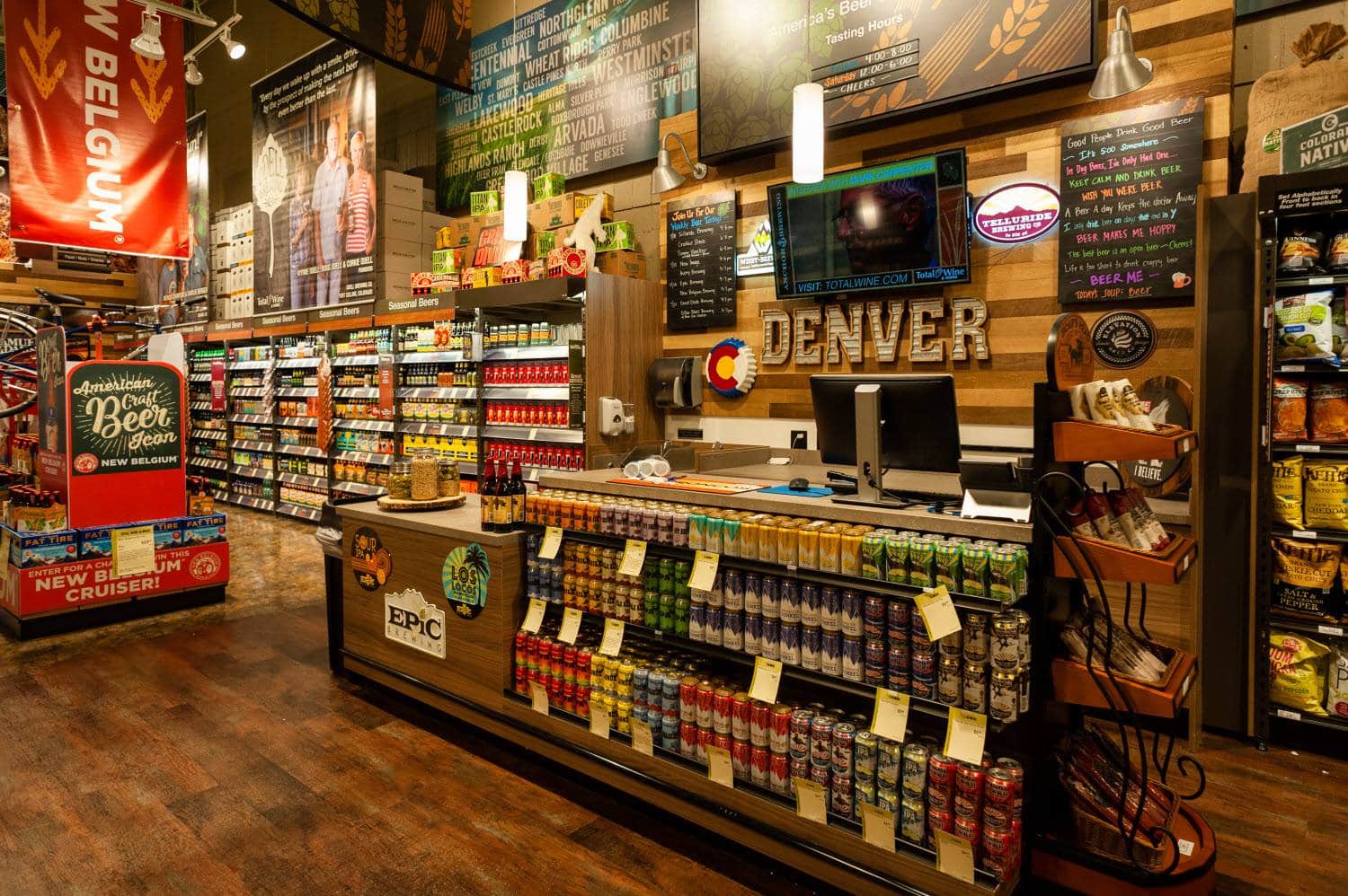 Tasting counter at Total Wine & More in Denver off of Evans Avenue. Variety of drinks on the shelves in front of the counter and marquee-style letters spelling out Denver behind