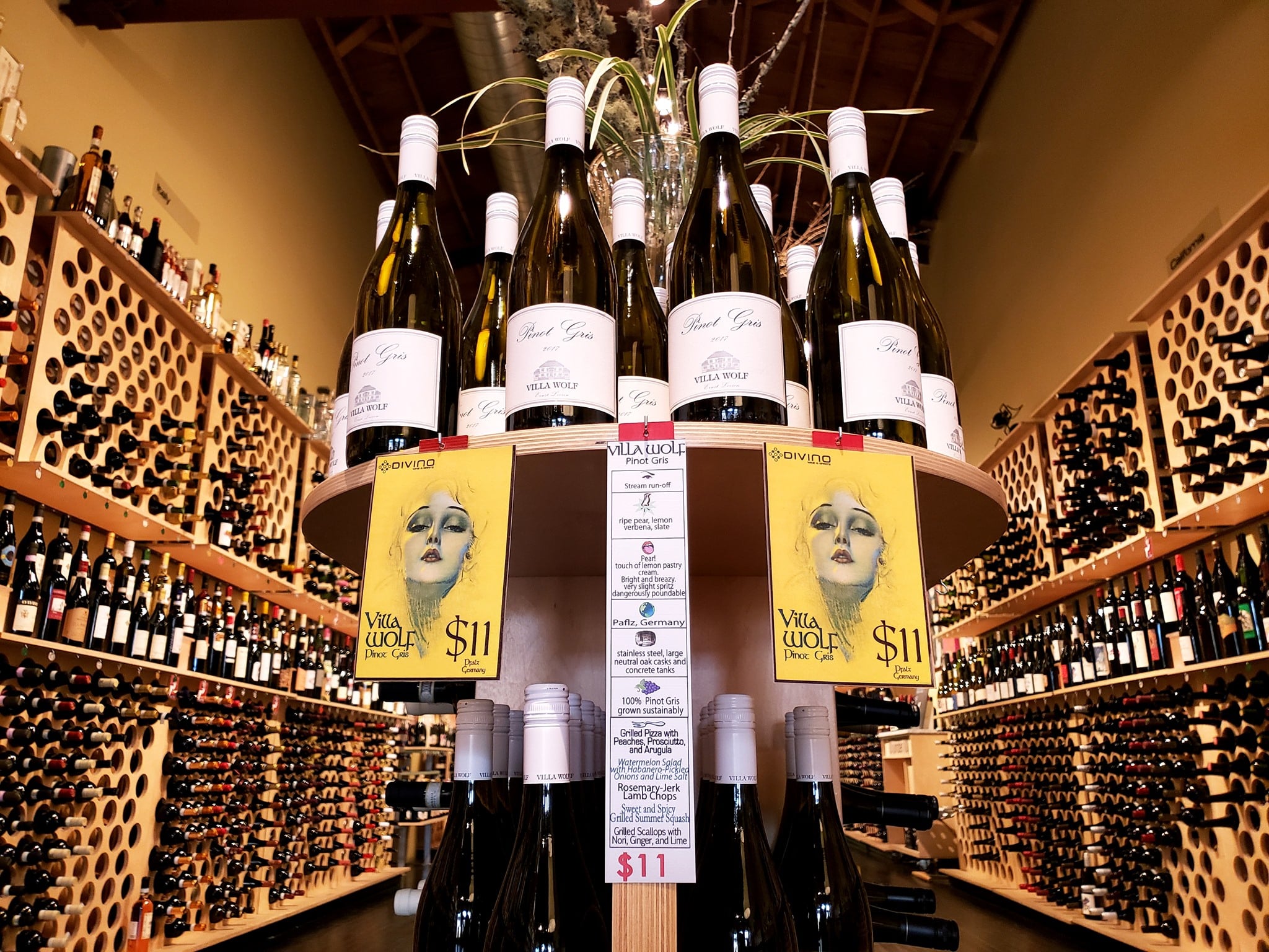 Round shelf display of $11 wine at Divino Wine and Spirits in Denver. Background is two walls lined with dozens of bottles of wine