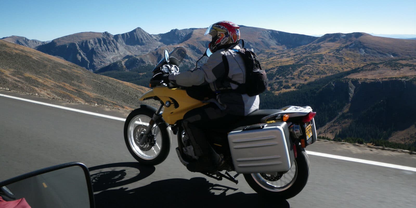 Motorcycle rider on yellow bike cruising along a high elevation road in Rocky Mountain National Park in central Colorado