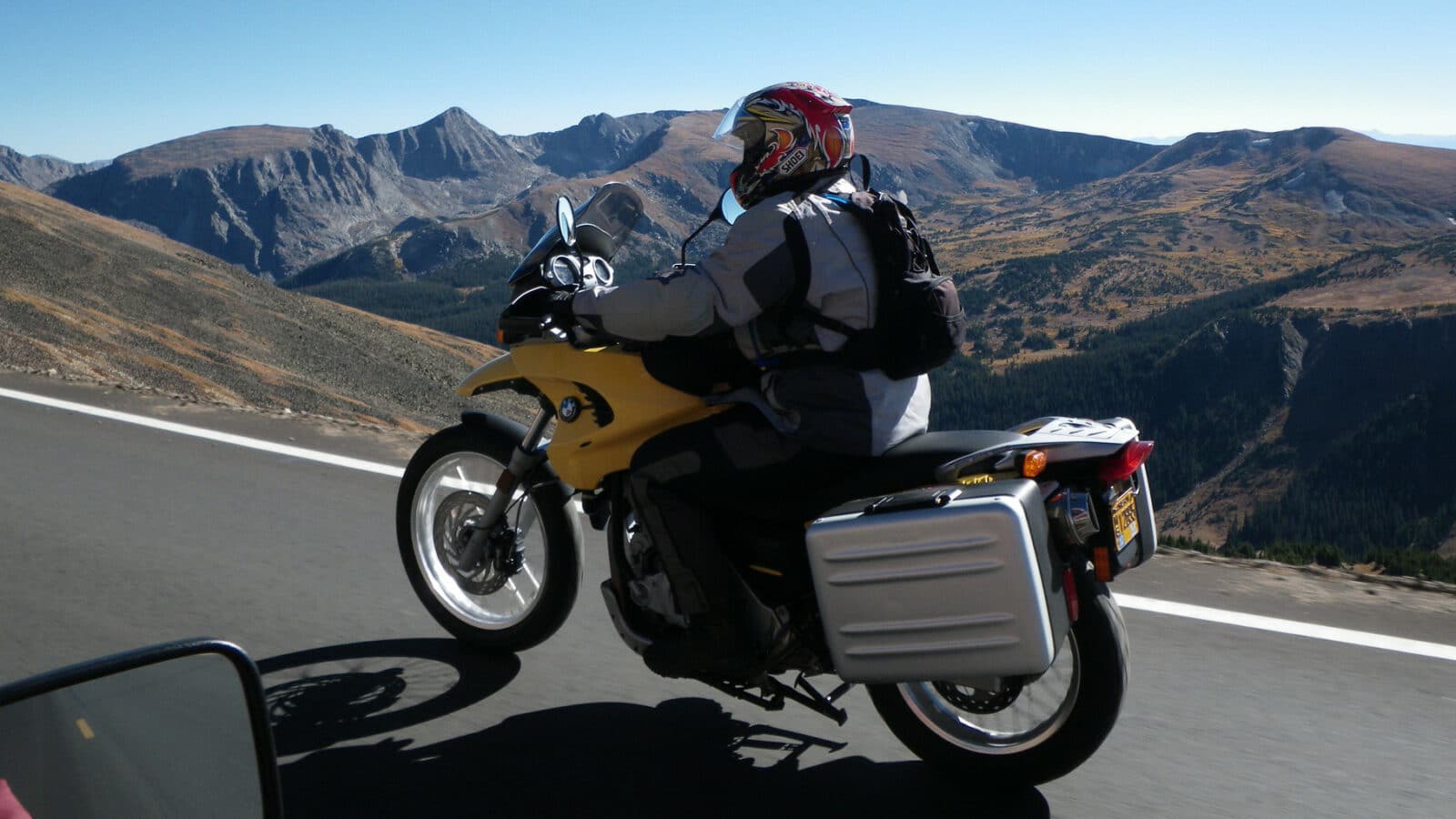 Motorcycle rider on yellow bike cruising along a high elevation road in Rocky Mountain National Park in central Colorado