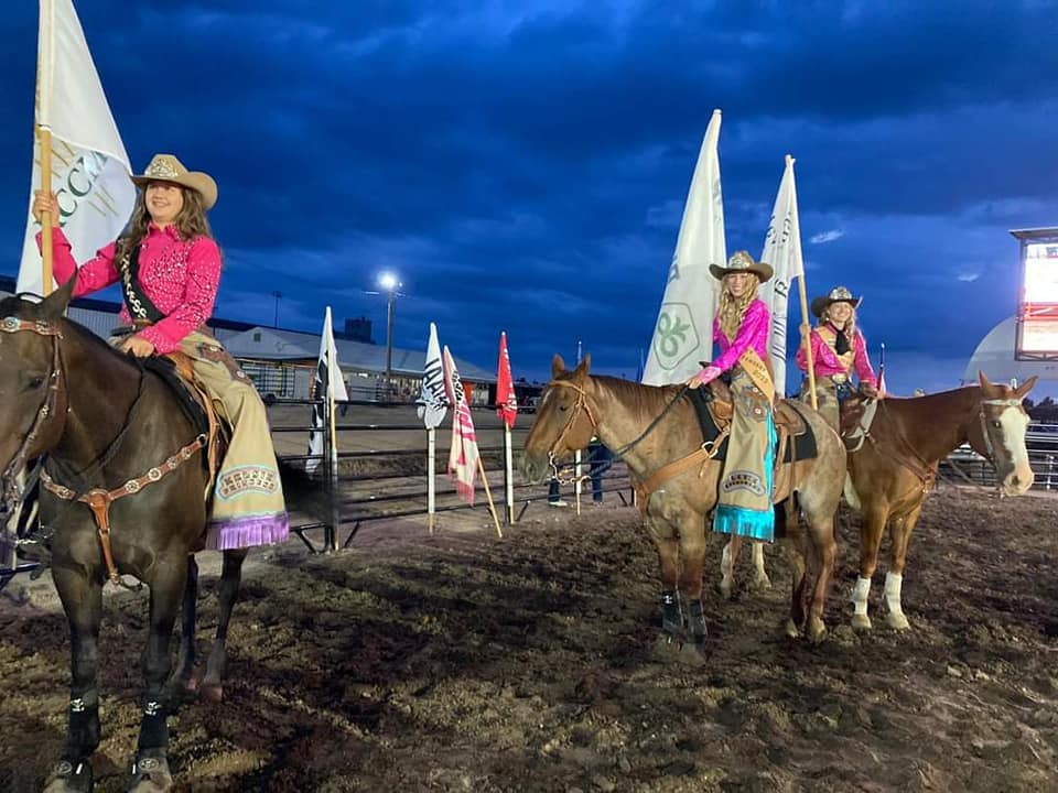 Three people wearing pink shirts sitting on horses at the Kit Carson County Fair and Rodeo for Tough Enough to Wear Pink night