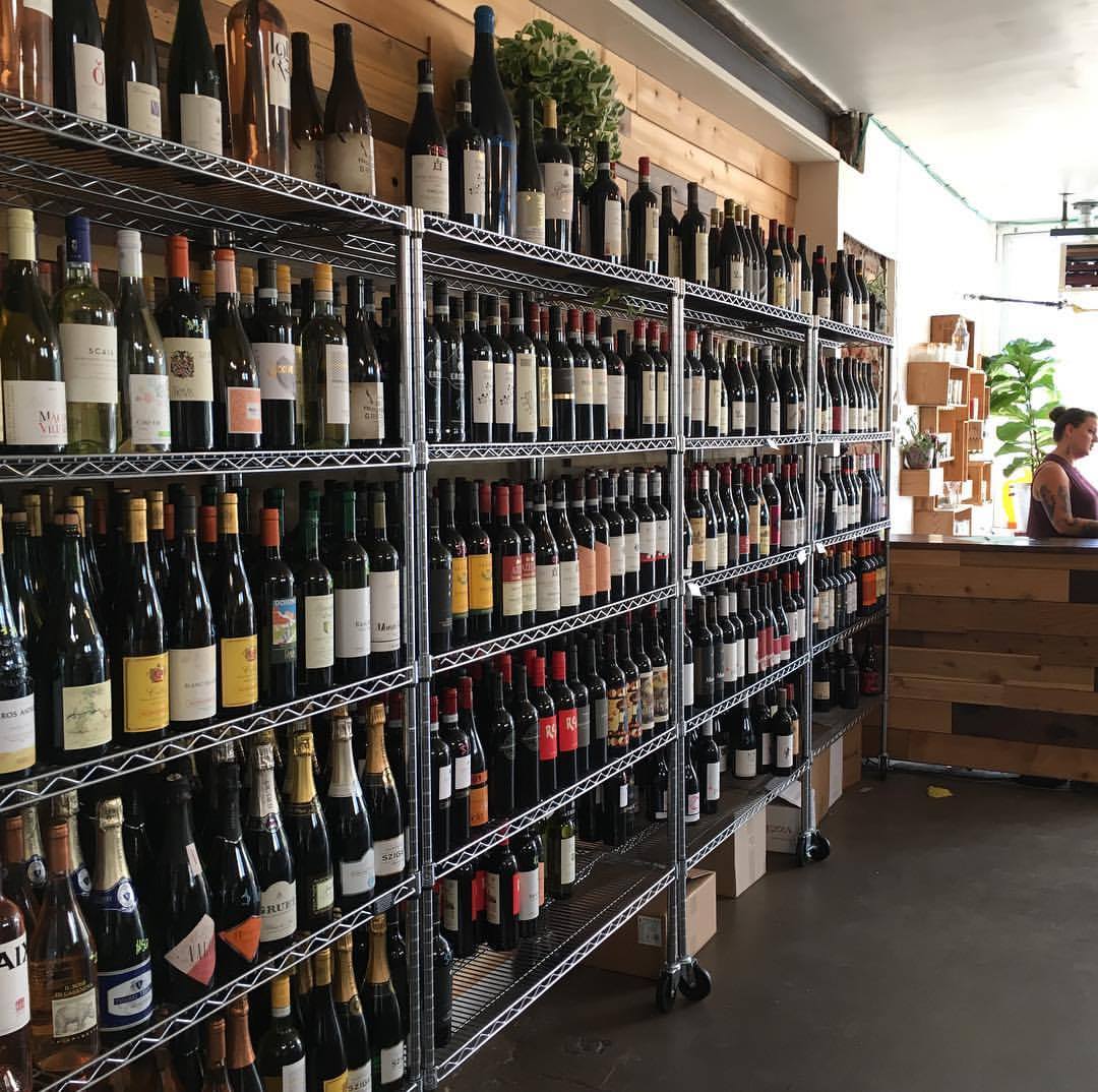 5 tiered metal shelving filled with bottles of wine at Proof Wine and Spirits in Denver. 