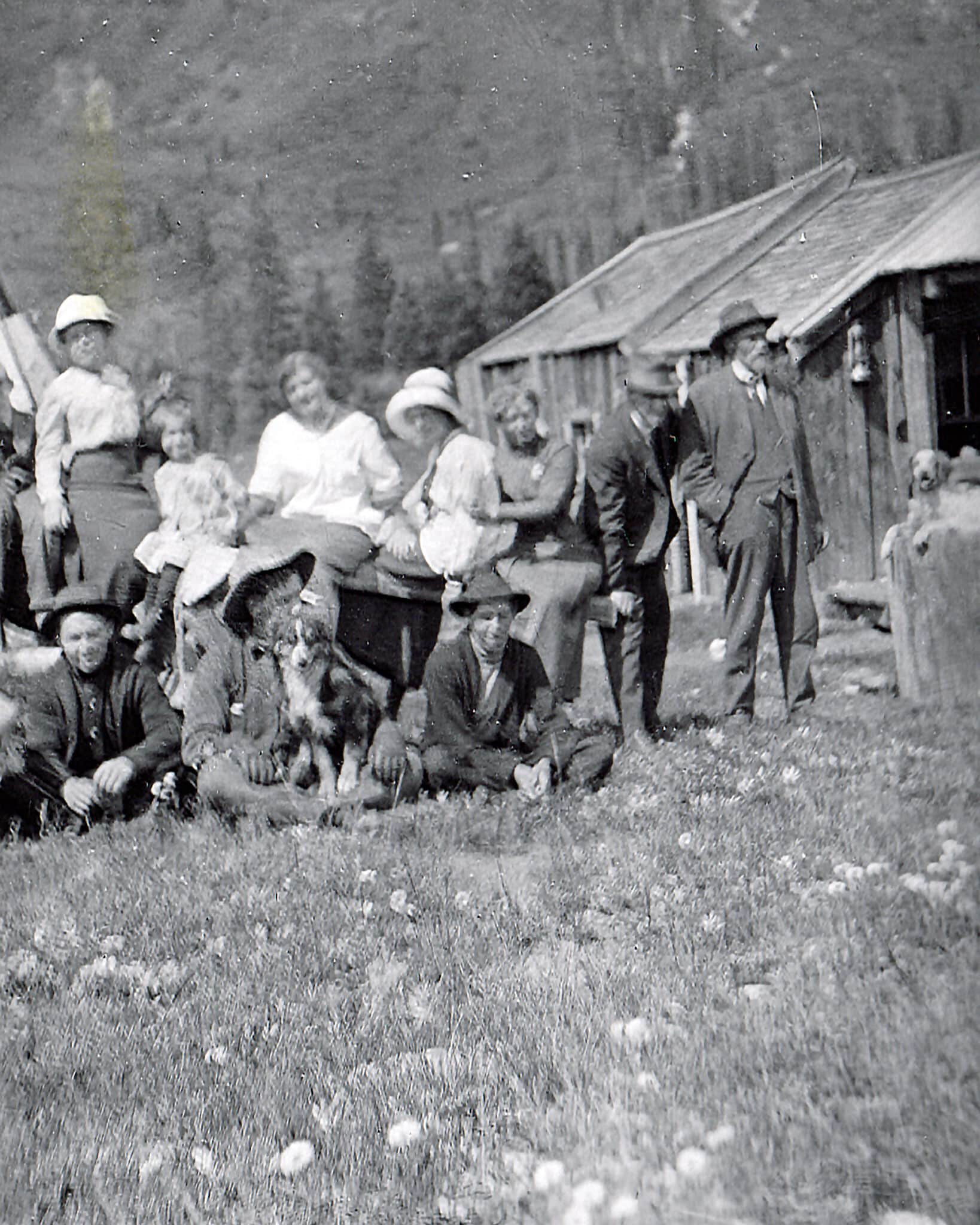 Group of people stand and sit on grass for photo in Gothic, Colorado in 1915