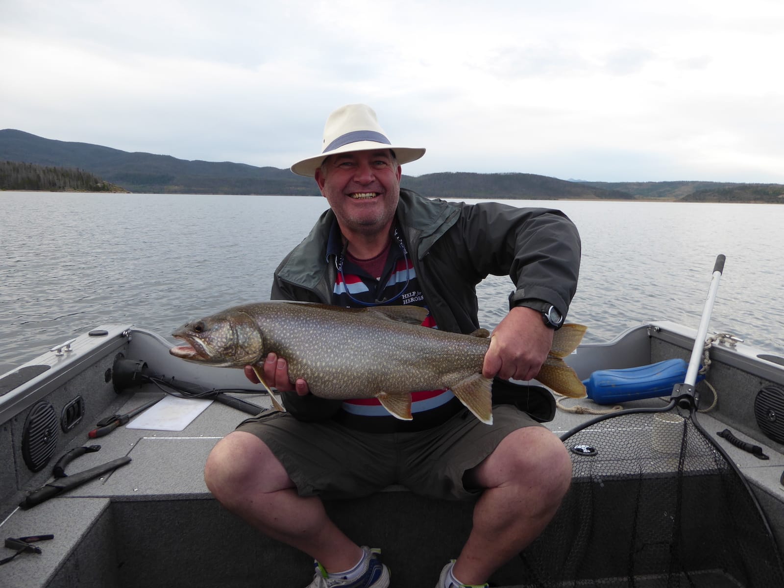 man holds up a large fish on a boat in Lake Granby guided fishing trip