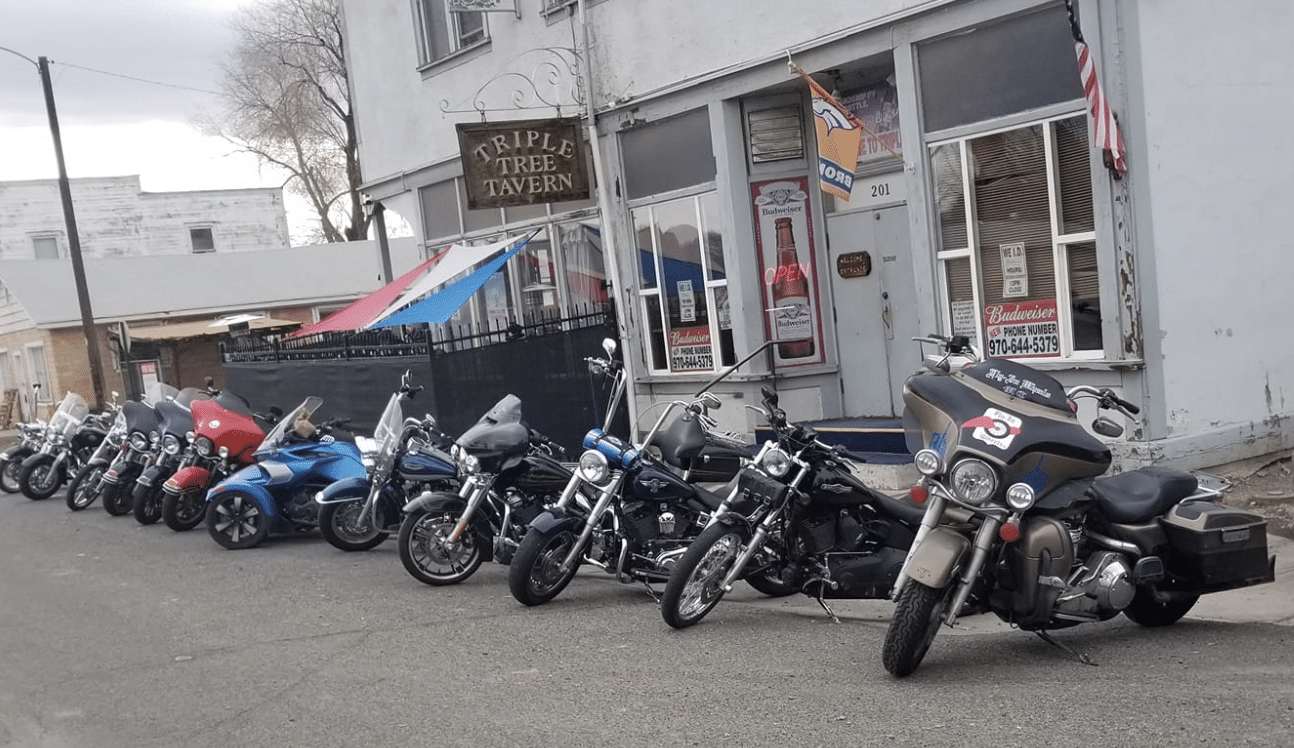 Motorcycles parked in front of a small local dive bar called the Triple Tree Tavern in Clifton, Colorado