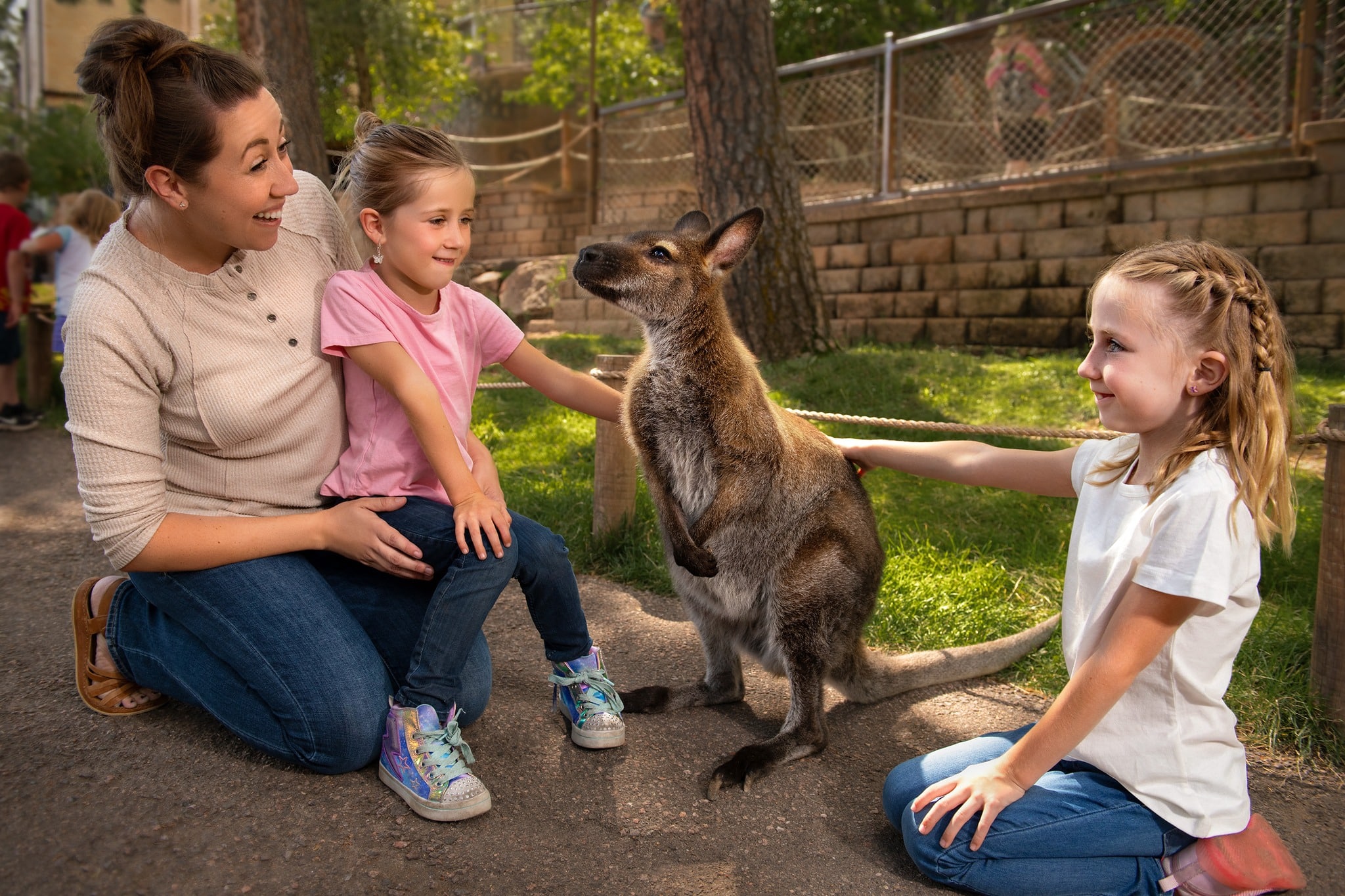 Two children and an adult crouched around a kangaroo at the Cheyenne Mountain Zoo.