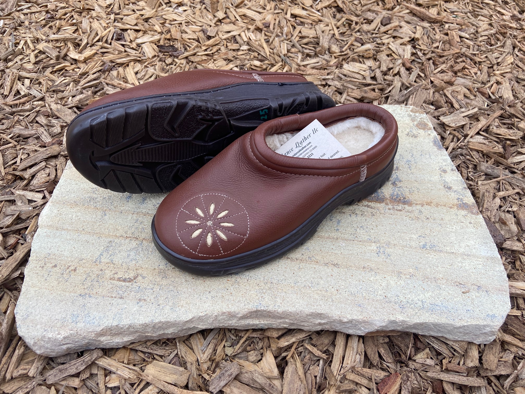 Women's Sundance Sheepskin & Leather clogs on a flat rock