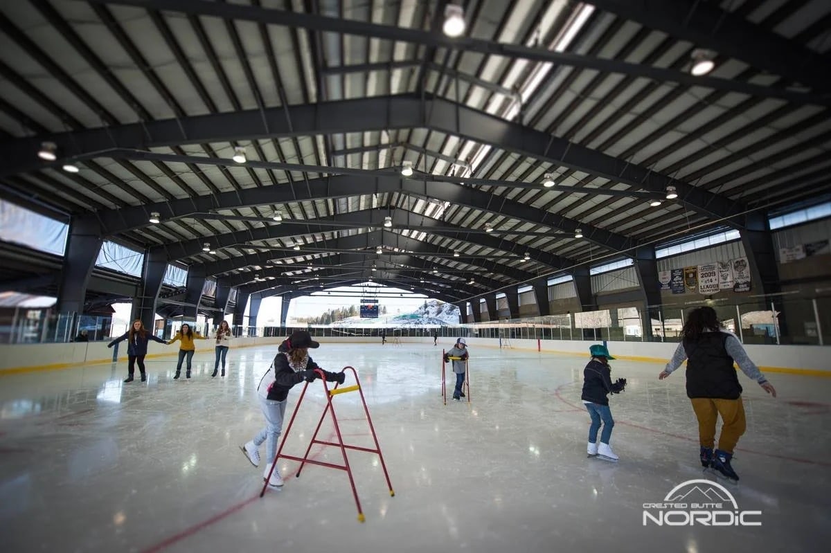 people ice skating inside the Big Mine Ice Arena in Crested Butte