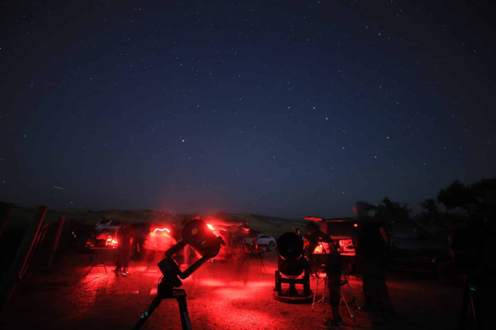 Group with red lights under the night sky with Astro Tours