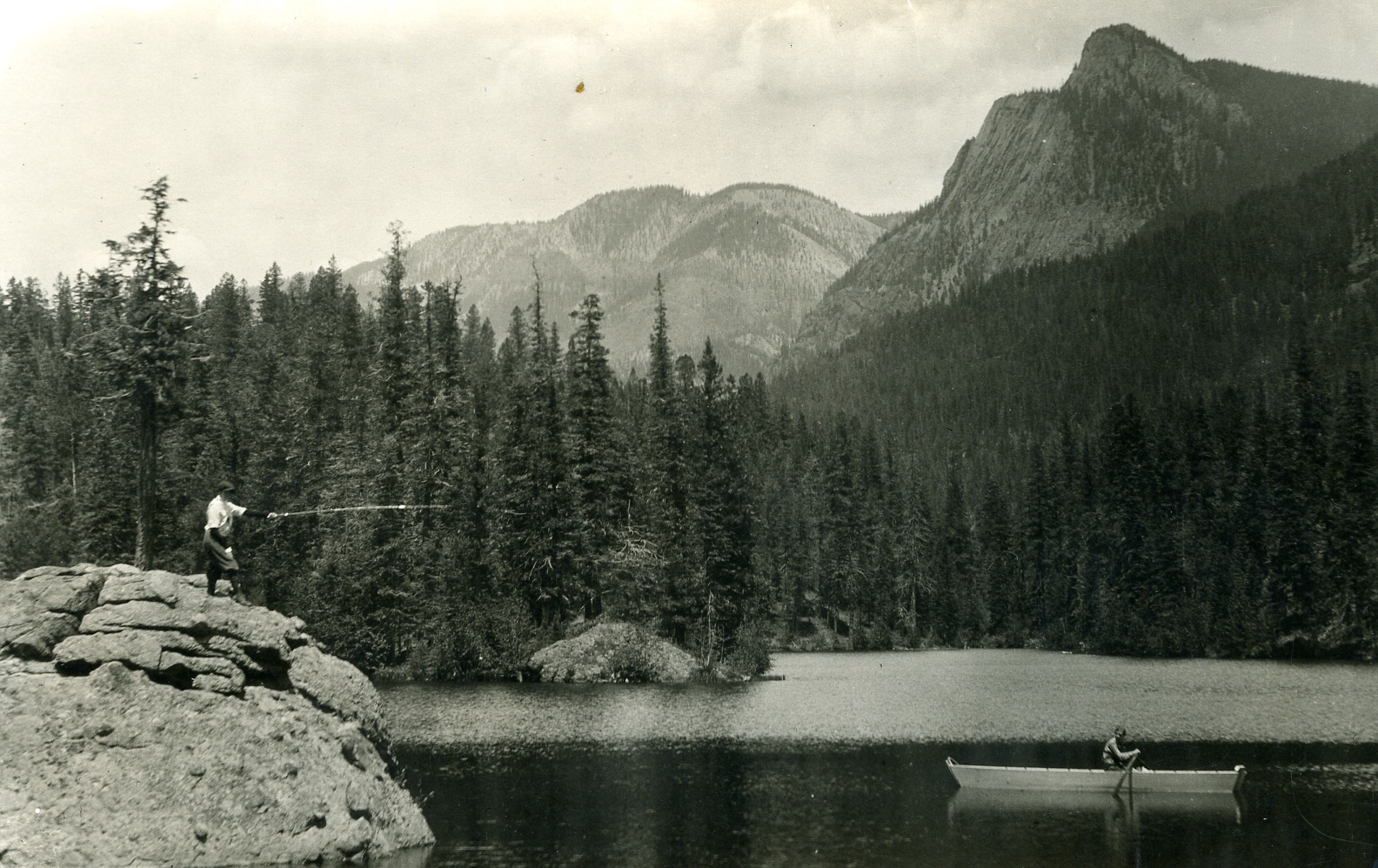 vintage black and white photo of a man casting a fishing line off a giant boulder on the edge of Borns Lake in Southwest Colorado