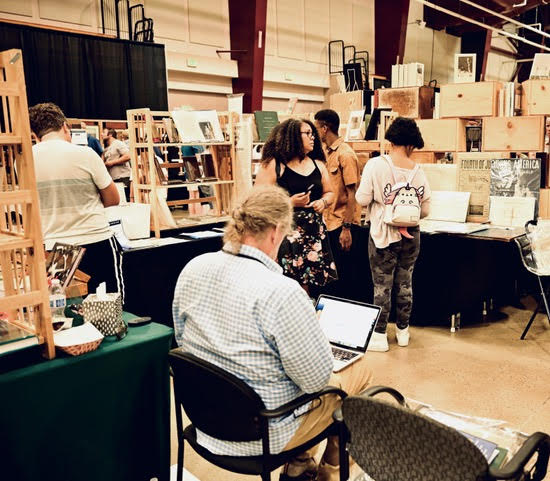 man works on a laptop at the at the Rocky Mountain Book and Paper Fair in Castle Rock, CO