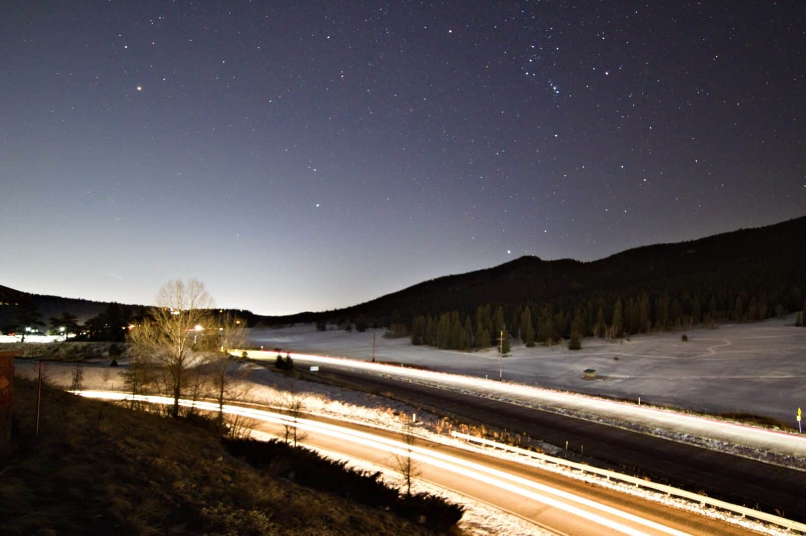 Light streaks on a highway in winter in Colorado with stars in the sky