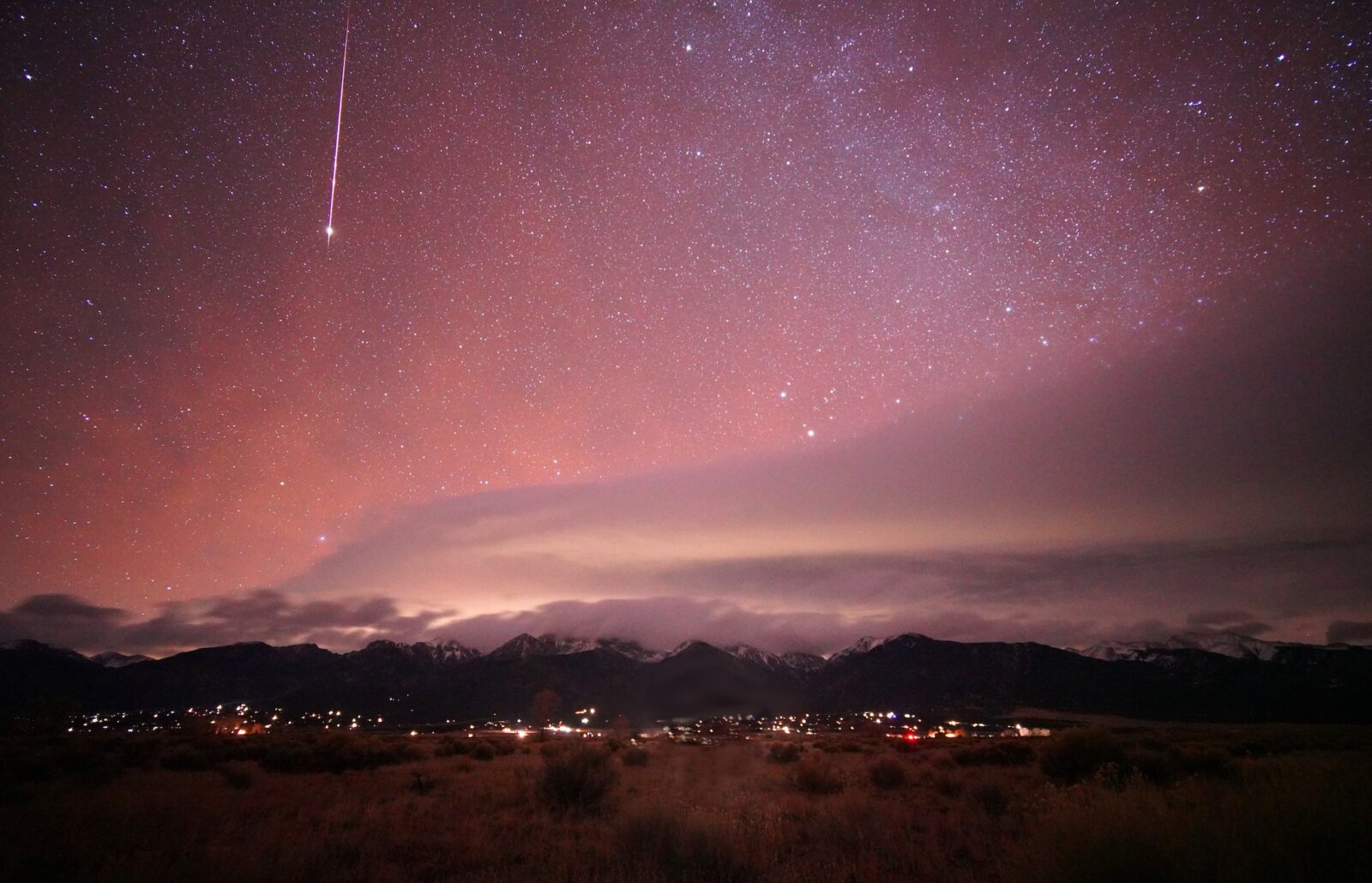 pink star lit sky above Crestone, Colorado with mountains rising above the town