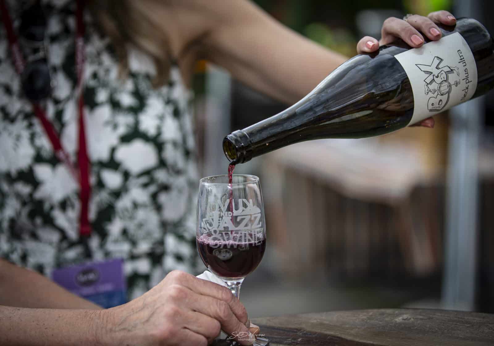 lady pours a glass of red wine at Ned Jazz & Wine Fest