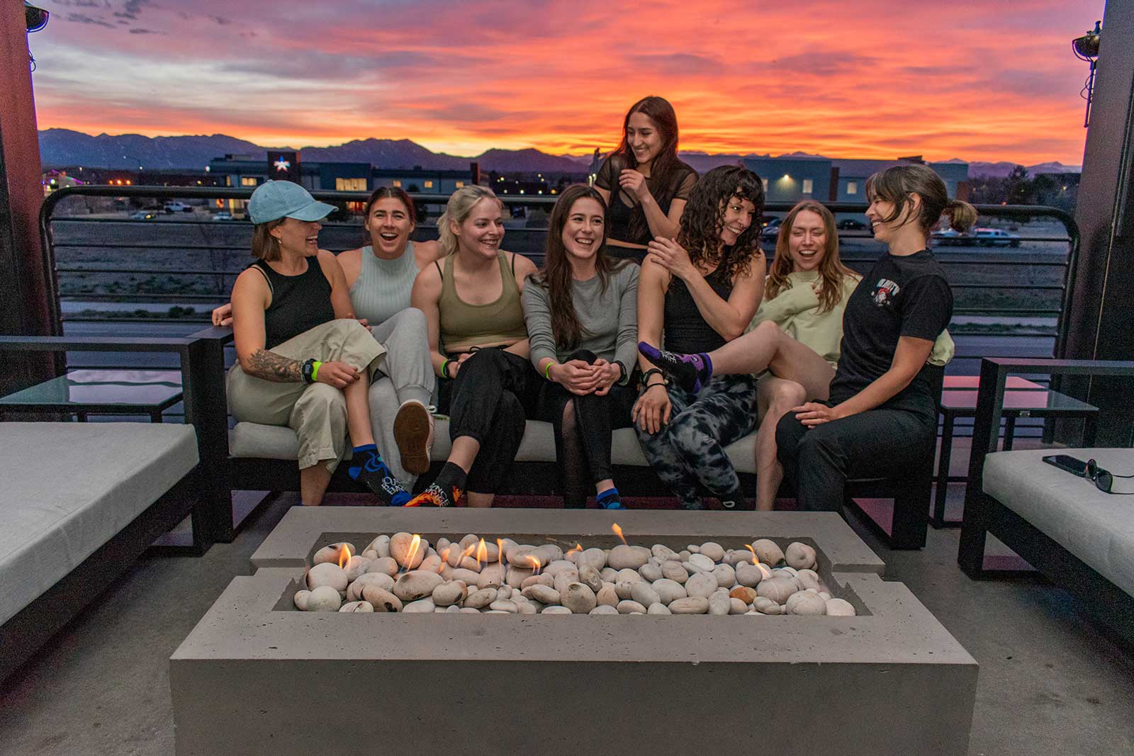 women sit on a couch with mountain sunset in background at outdoor patio on Bounce Empire in Lafayette