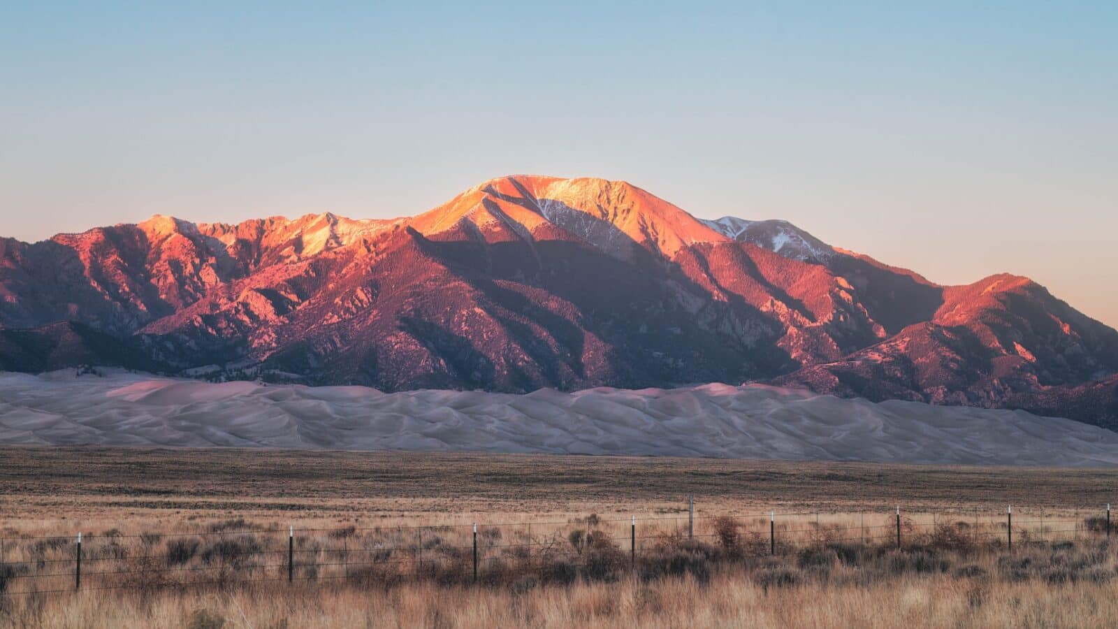 Alpenglow falls over the Great Sand Dunes and Sangre De Cristo Mountains behind them