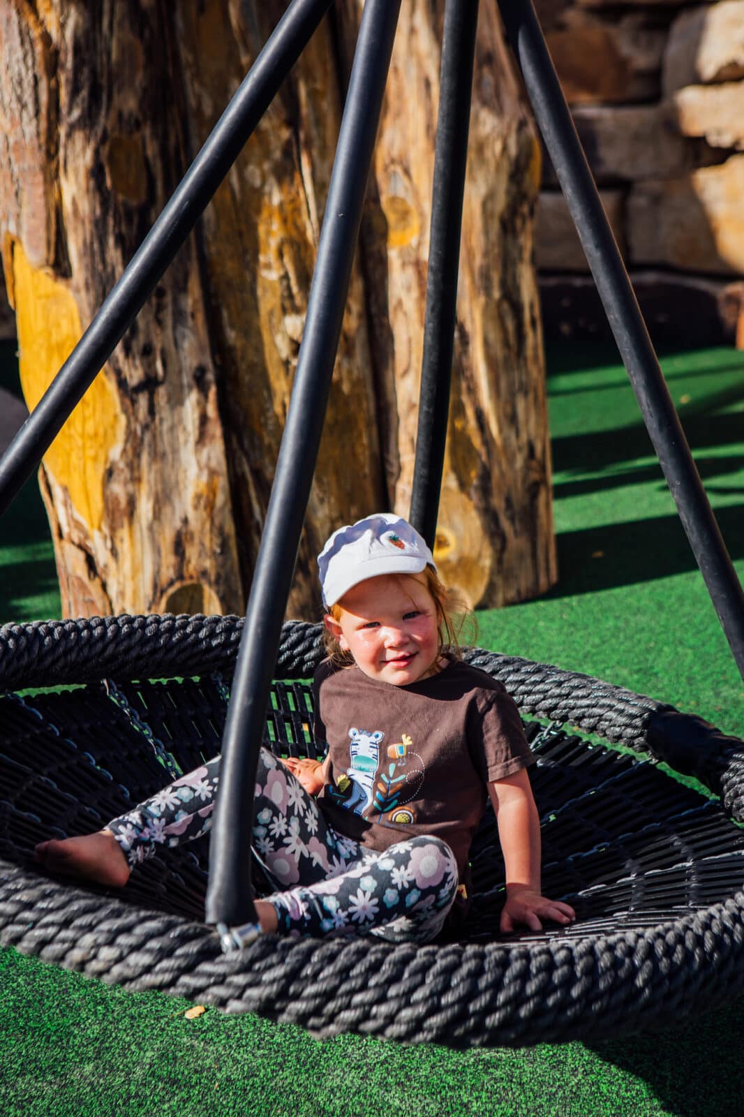 child sit on a circular swing in Idlewild Park, Winter Park