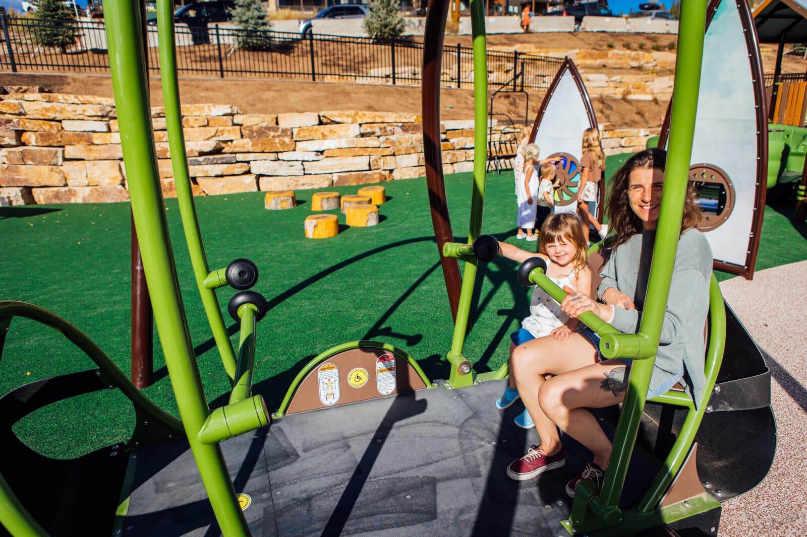 mom and daughter sit on an adaptive seesaw in Idlewild Park