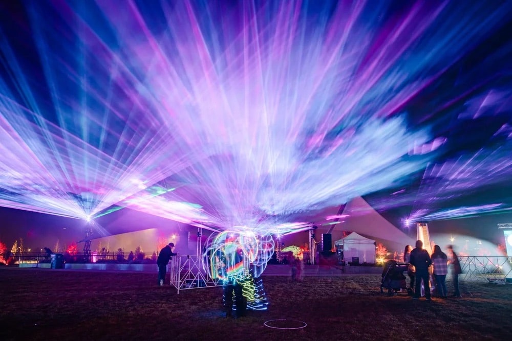 blue and pink lights shoot up into the sky at the Aurora Borealis Festival in Colorado