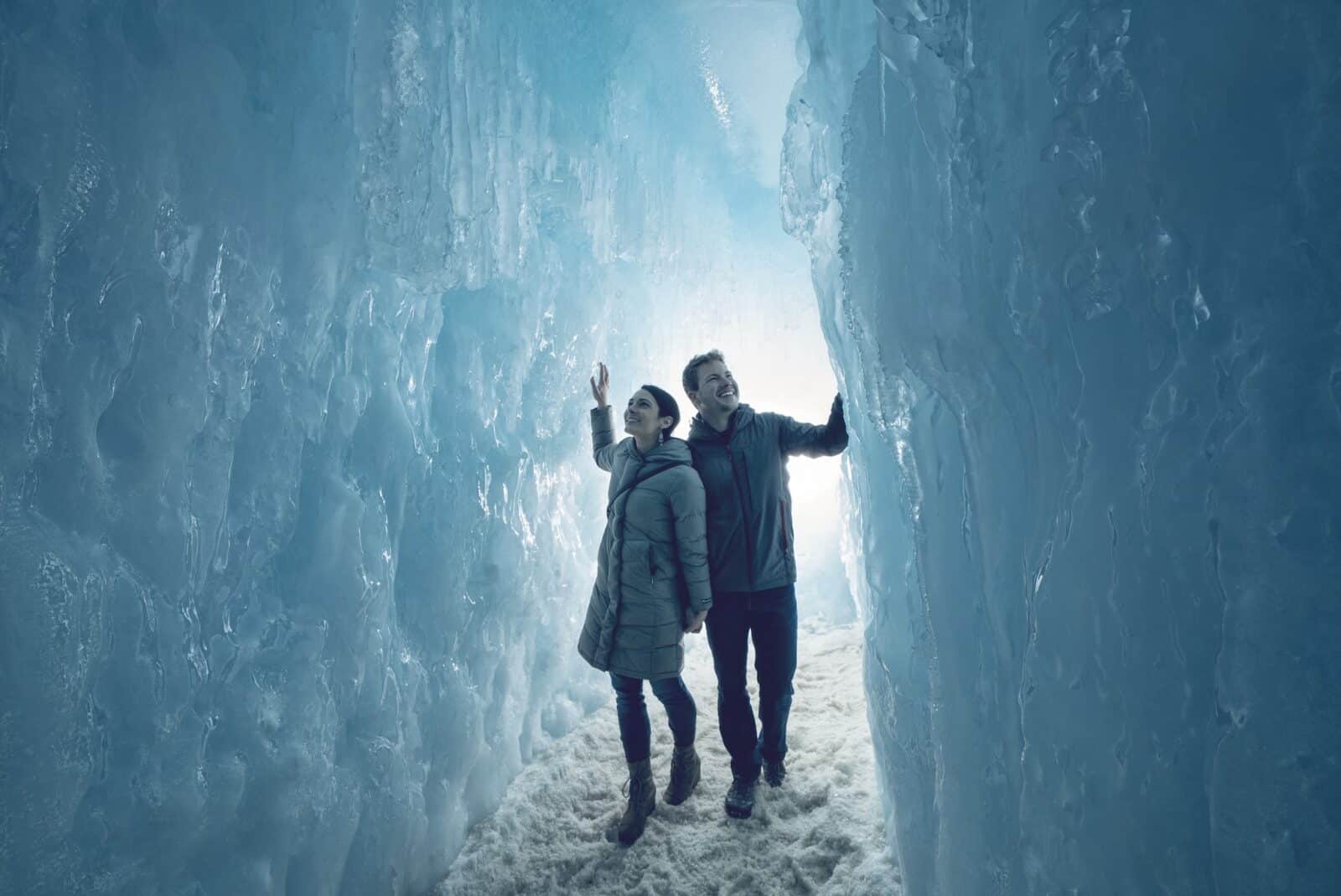couple walks through ice castles touching the walls in Colorado