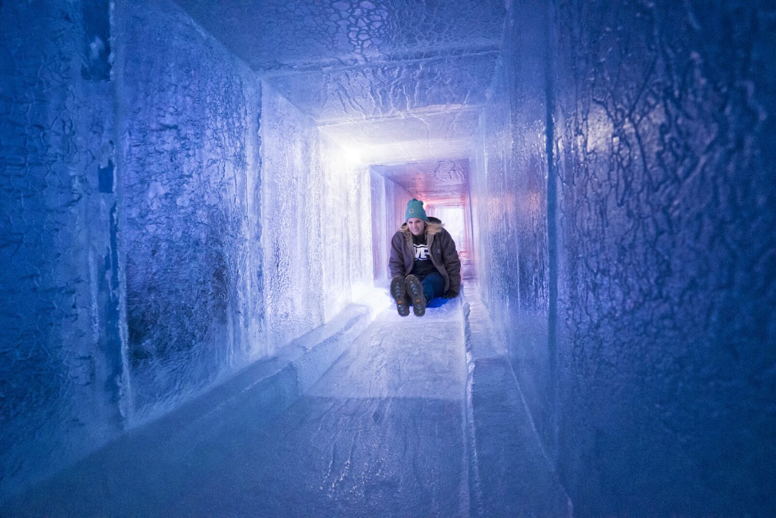 woman slides down a frozen slide in Ice Castles