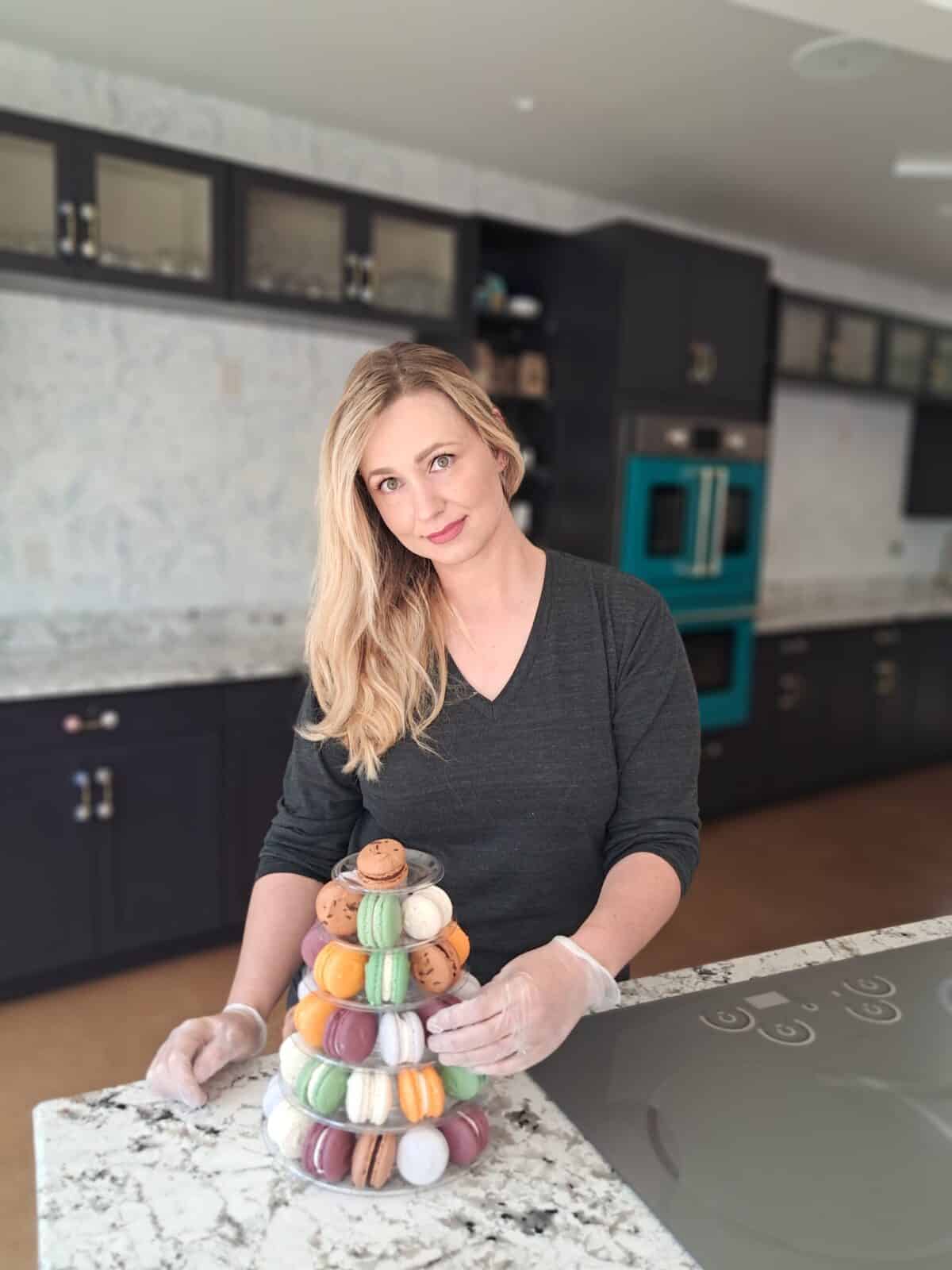 Jamie Picasarri stands next to a display of macarons from Denver Macaron