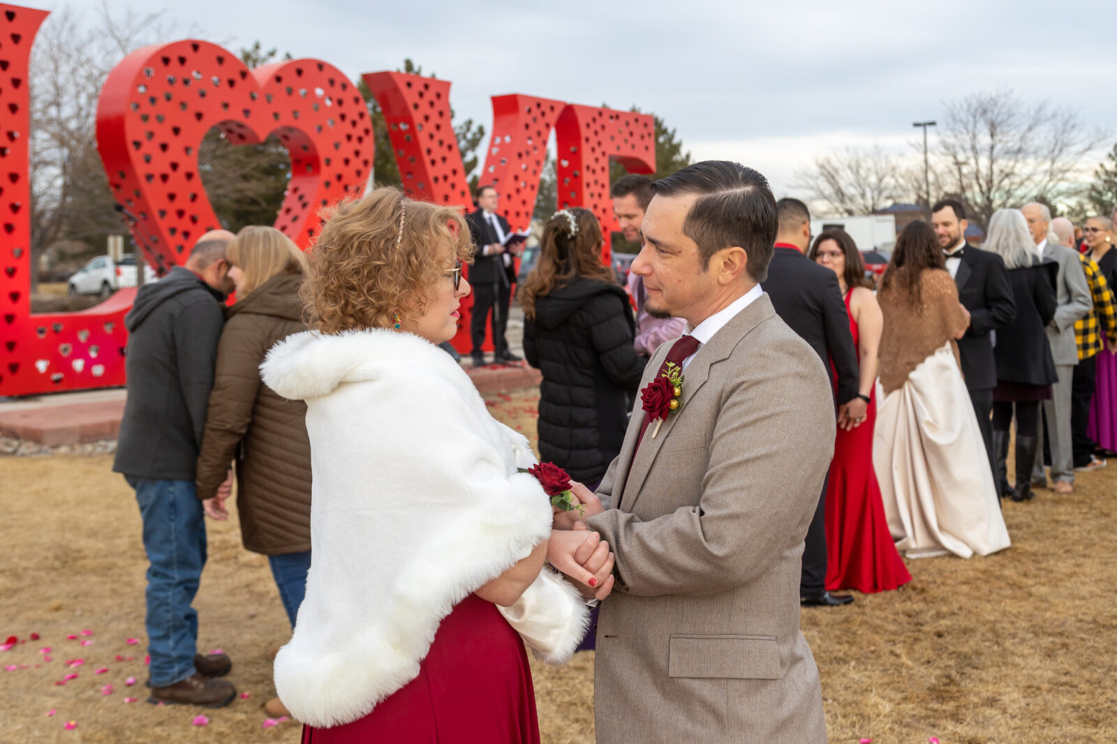 woman and man holding hands outside in front of "LOVE" sign at the Loveland Valentine's Day Group Wedding