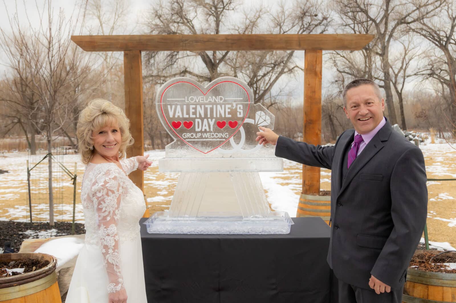 a couple point at an ice heart for the Loveland Valentine's Day Group Wedding