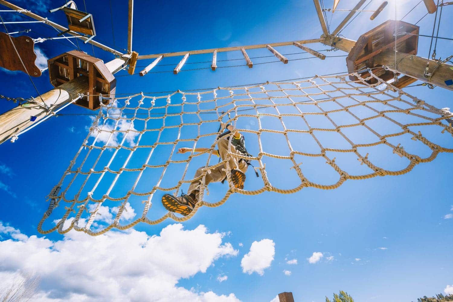 looking up at someone crossing the rope ladder at the Open Air Adventure Park in Estes Park